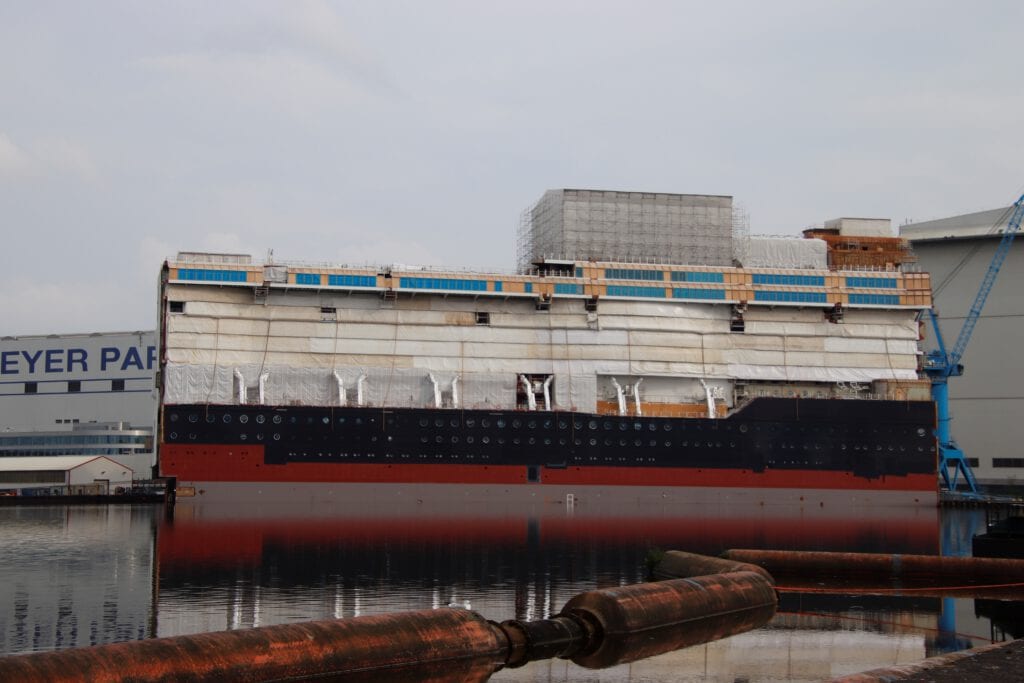Ein 140 Meter langes Schwimmteil der Disney Wish liegt bereits vor der Meyer Werft in Papenburg. Noch eingerüstet und verhüllt ist der technisch notwendige Schornstein des Schiffes. Foto: Christoph Assies
