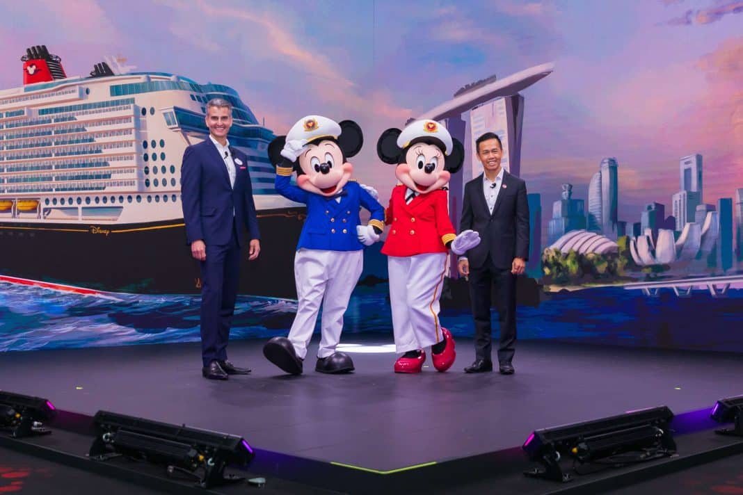Josh D’Amaro, Vorsitzender von Disney Parks, Experiences and Products (links), und S. Iswaran, Singapurs Verkehrsminister umrahmen Micky und Minnie Maus. Foto: © Disney Cruise Line