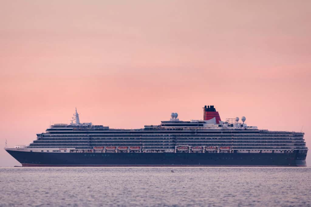 QUEEN VICTORIA liegt auf Reede, während die Sonne aufgeht. Foto: © Cunard Line / Christopher Ison
