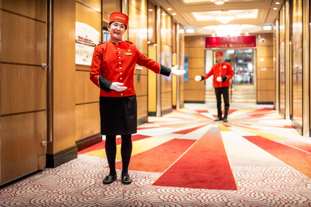 Bellhops begrüßen die Passagiere während der Einschiffung an Bord der Queen Mary 2. Foto: © Cunard Line / Christopher Ison