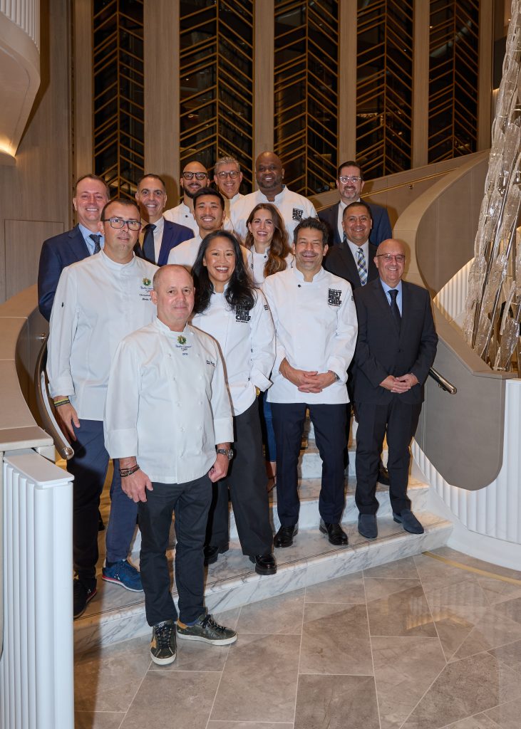 Eine ganze Menge Paten in Patinnen zusammen mit den Executive Culinary Diretoren Eric Barale (vorne links) und Alexis Quaretti (2. Reihe links), sowie Jason Montague, Chief Luxury Officer Norwegian Cruise Line Holdings (3. Reihe links), Bernhard Klotz (Vice President of Culinary Operations, letzte Reihe Mitte). Dazu die Taufparten Aisha Ibrahim, George Mendes, Calvin Eng, Katie Button, Lawrence “LT” Smith und Tavel Bristol-Joseph, Foto: © Oceania Cruises