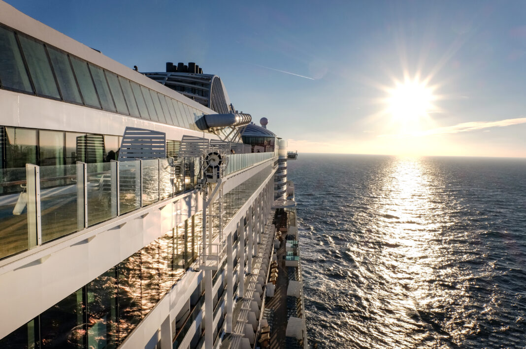Kreuzfahrtschiff auf dem Ozean fährt in Richtung Sonnenuntergang - mit Sonnenstrahlen und Lensflares